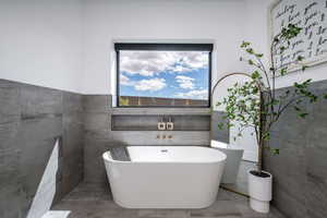 Bathroom with a freestanding tub and tile walls