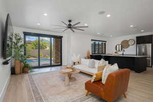 Living room with light wood-type flooring, a ceiling fan, and recessed lighting
