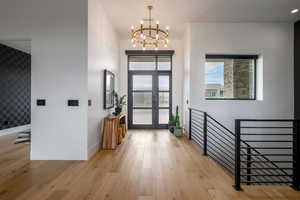 Foyer entrance featuring light wood finished floors, french doors, and a chandelier