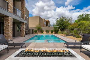 Integrated pool / hot tub with a patio, a fenced backyard, and a balcony