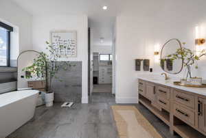 Full bath featuring vanity, a spacious closet, a freestanding tub, and recessed lighting