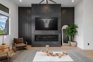 Living room with a large fireplace, light wood-style floors, an accent wall, recessed lighting, and wood walls