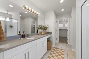 Master bath with quartz countertop, walk-in shower, and tile floors