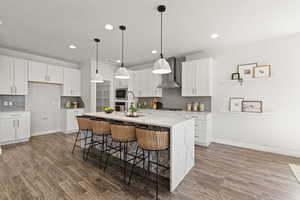 Kitchen featuring waterfall quartz island, gas countertop range, range hood, pendant lighting, soft close drawers and cabinets