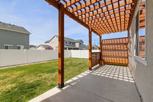 Fully fenced backyard with automatic sprinkler system and custom pergola covering patio