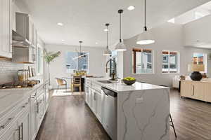 Kitchen featuring waterfall quartz island, gas countertop range, range hood, pendant lighting, soft close drawers and cabinets