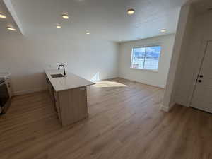 Kitchen featuring a peninsula, light wood-type flooring, stainless steel electric range oven, light stone countertops, and open floor plan