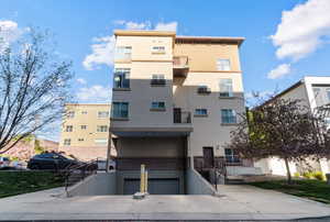 View of apartment building / complex featuring an attached garage and concrete driveway west entrance/exit.