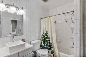 Bathroom featuring tile walls, vanity, and shower / bath combination.