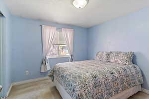 Bedroom with light carpet and a textured ceiling