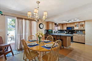 Dining room featuring a chandelier, healthy amount of natural light, light wood-style flooring, and crown molding
