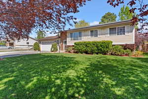 Tri-level home featuring an attached garage, a front yard, and driveway