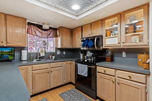 Kitchen featuring electric range, stainless steel microwave, an ornate ceiling, dark countertops, and light wood finish cabinetry