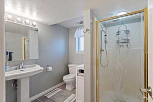 Full bathroom featuring a textured ceiling, a shower stall, and light tile patterned floors