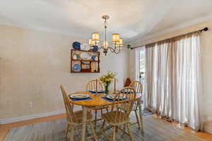 Dining room featuring light wood-style flooring, a chandelier, and crown molding