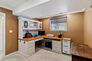 Home office with light colored carpet, a textured ceiling, and ornamental molding