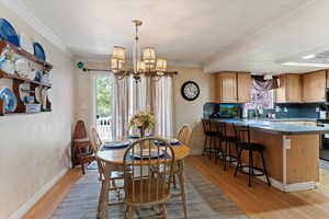 Dining room featuring suspended lighting, light wood finished floors, plenty of natural light, and crown molding