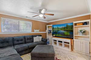 Living area with ceiling fan, a textured ceiling, and ornamental molding