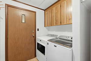 Laundry room with cabinet space, a textured ceiling, separate washer and dryer, and ornamental molding