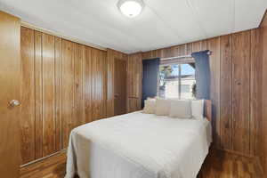 Bedroom featuring a closet, a textured ceiling, wood finished floors, and wooden walls