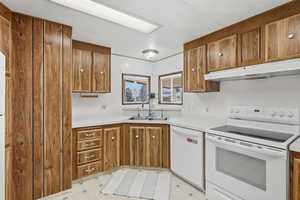 Kitchen with white appliances, light flooring, light countertops, and wood finish cabinetry