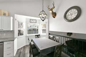 Dining room with dark wood-style flooring and hanging lights
