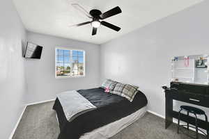 Bedroom with dark colored carpet and ceiling fan