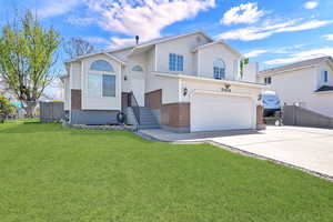 Split level home with brick siding, an attached garage, and concrete driveway
