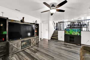 Living room with ceiling fan, dark wood-style flooring, and a textured ceiling