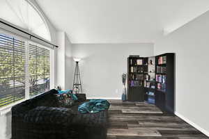 Sitting room with dark wood finished floors and lofted ceiling