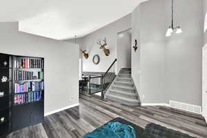 Stairs with a high ceiling, wood finished floors, and hanging lights