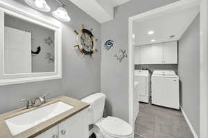 Half bathroom featuring vanity, washing machine and dryer, and recessed lighting