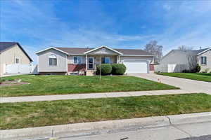 Single story home with an attached garage, concrete driveway, a gate, a porch, and brick siding