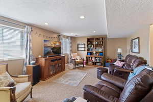 Living room featuring light carpet, a textured ceiling, and recessed lighting