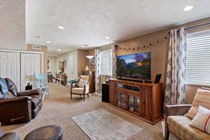 Living area featuring light colored carpet, a textured ceiling, and recessed lighting