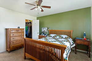 Bedroom featuring carpet, ceiling fan, and a spacious closet