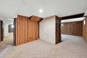 Additional living space with wood walls and light carpet
