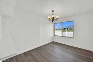 Unfurnished dining area with a mountain view, brick wall, dark wood-style floors, and a chandelier