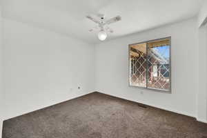 Unfurnished room with ceiling fan and dark carpet