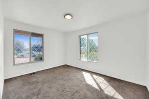 Spare room with baseboards and dark carpet