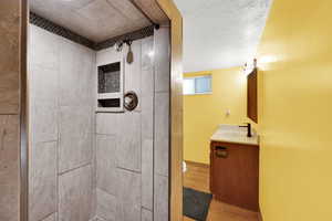 Full bathroom with vanity, a shower stall, light wood finished floors, and a textured ceiling