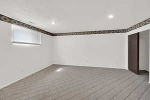 Basement with carpet floors, a textured ceiling, and recessed lighting