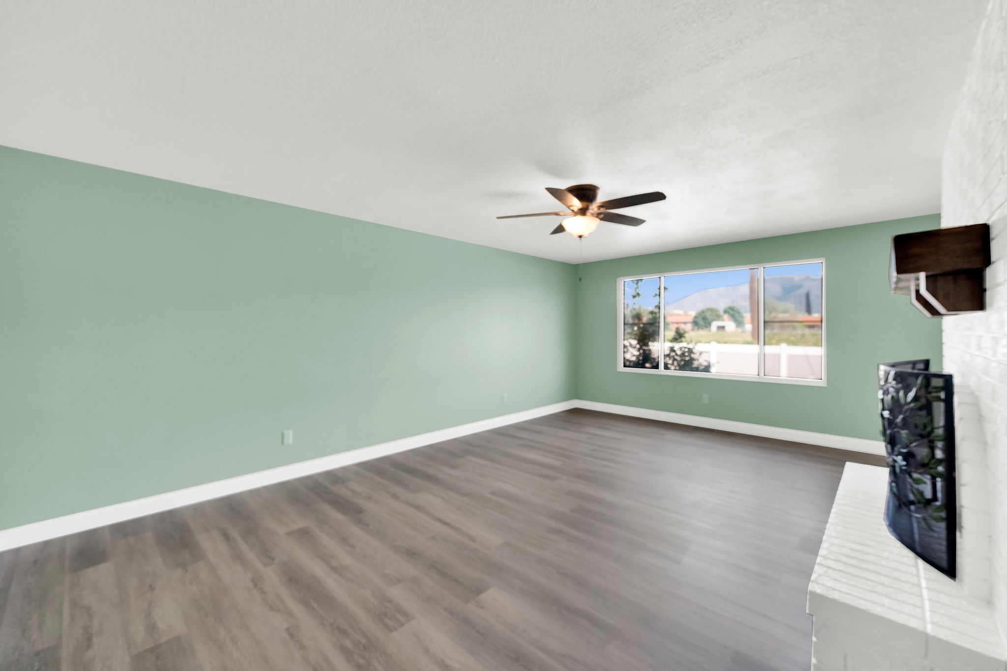 Unfurnished living room with a fireplace, dark wood-type flooring, and ceiling fan