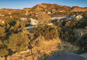 Aerial view of property and surrounding area with mountains and property parcel outlined