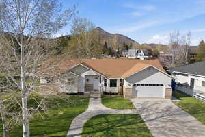Ranch-style home with a mountain view, a garage, driveway, and brick siding