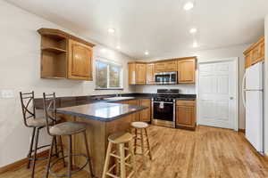 Kitchen featuring a peninsula, light wood finished floors, stainless steel appliances, a breakfast bar area, and recessed lighting