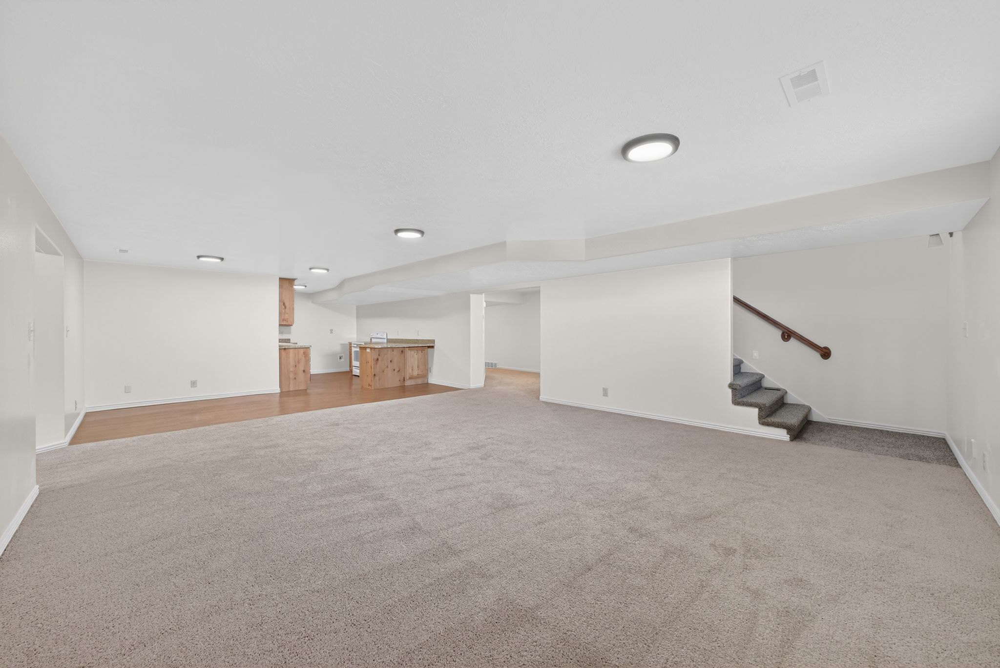 Finished basement featuring stairway and light carpet