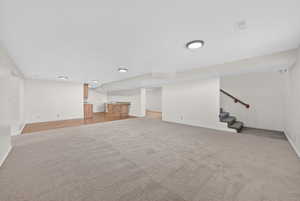 Finished basement featuring stairway and light carpet