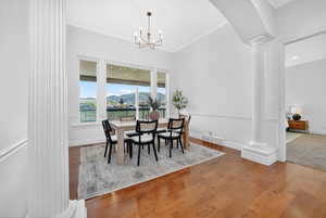 Dining area with decorative columns, a mountain view, hardwood / wood-style floors, arched walkways, and hanging lights
