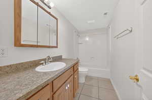 Bathroom featuring vanity, shower / bath combination, light tile patterned floors, and a textured ceiling